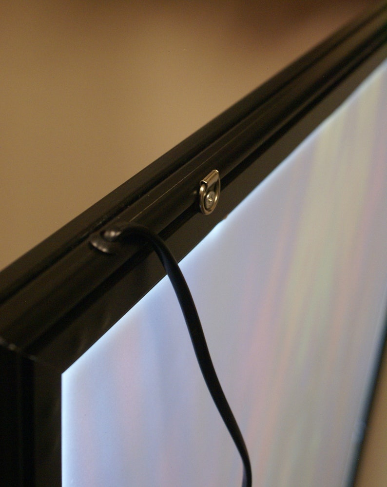 May include: A black framed light box with a white light panel and a black cord hanging from the top. The frame has a silver metal latch.