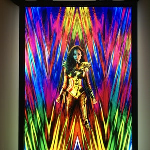 May include: A movie poster for Wonder Woman 1984, featuring Wonder Woman in a golden costume standing in front of a colorful, abstract background. The text "JUNE 5, 2020" and "#WW84" are at the bottom of the poster.