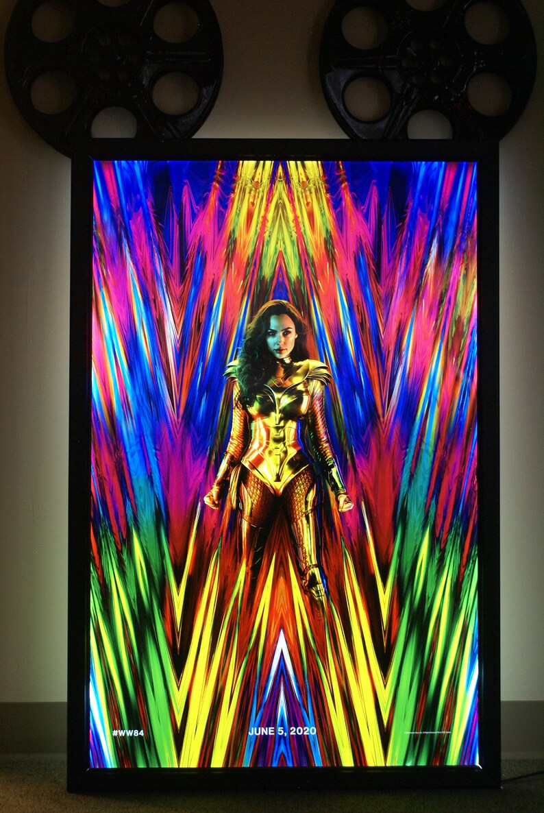 May include: A movie poster for Wonder Woman 1984, featuring Wonder Woman in a golden costume standing in front of a colorful, abstract background. The text "JUNE 5, 2020" and "#WW84" are at the bottom of the poster.