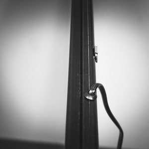 May include: A black metal rod with a silver metal hook and a black strap attached to it.