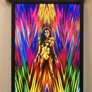 May include: A movie poster for Wonder Woman 1984 featuring Wonder Woman in a golden costume standing in front of a colorful, abstract background. The text "JUNE 5, 2020" and "#WW84" are at the bottom of the poster.