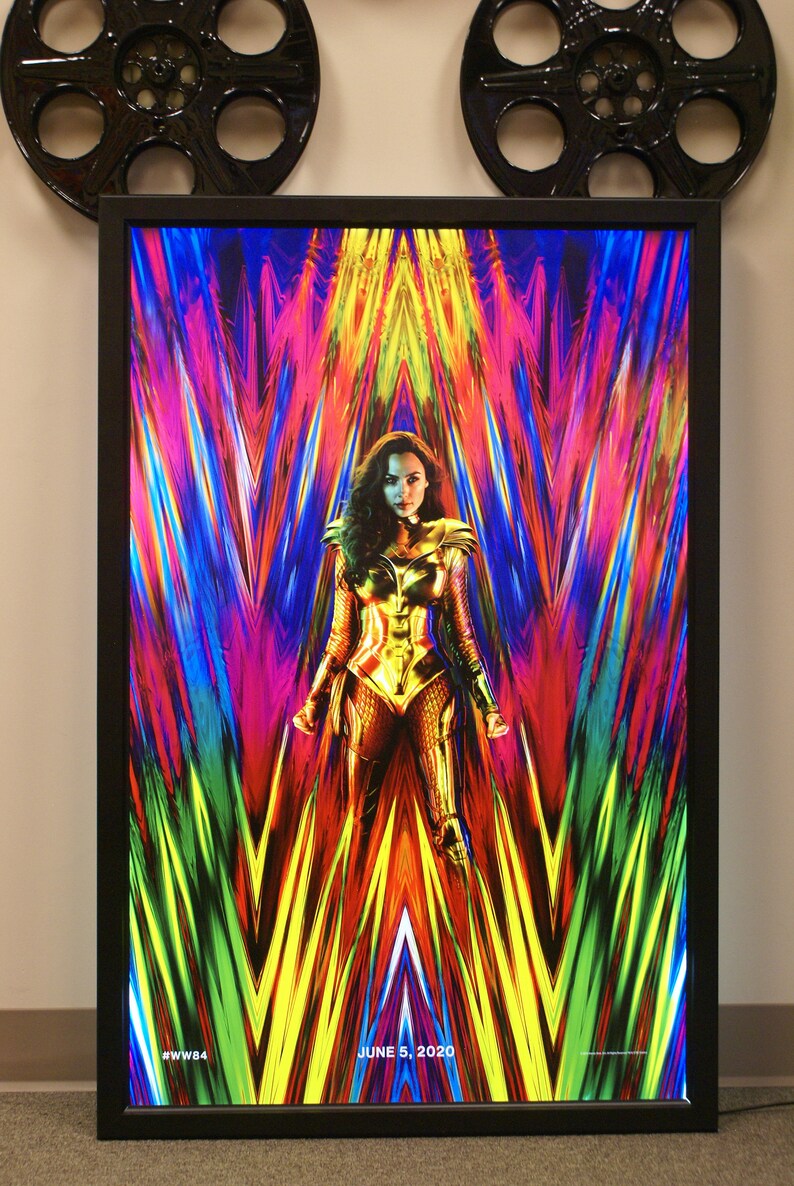May include: A movie poster for Wonder Woman 1984 featuring Wonder Woman in a golden costume standing in front of a colorful, abstract background. The text "JUNE 5, 2020" and "#WW84" are at the bottom of the poster.