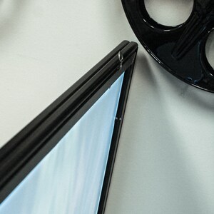 May include: A black picture frame with a light blue background. The frame is hanging on a white wall.