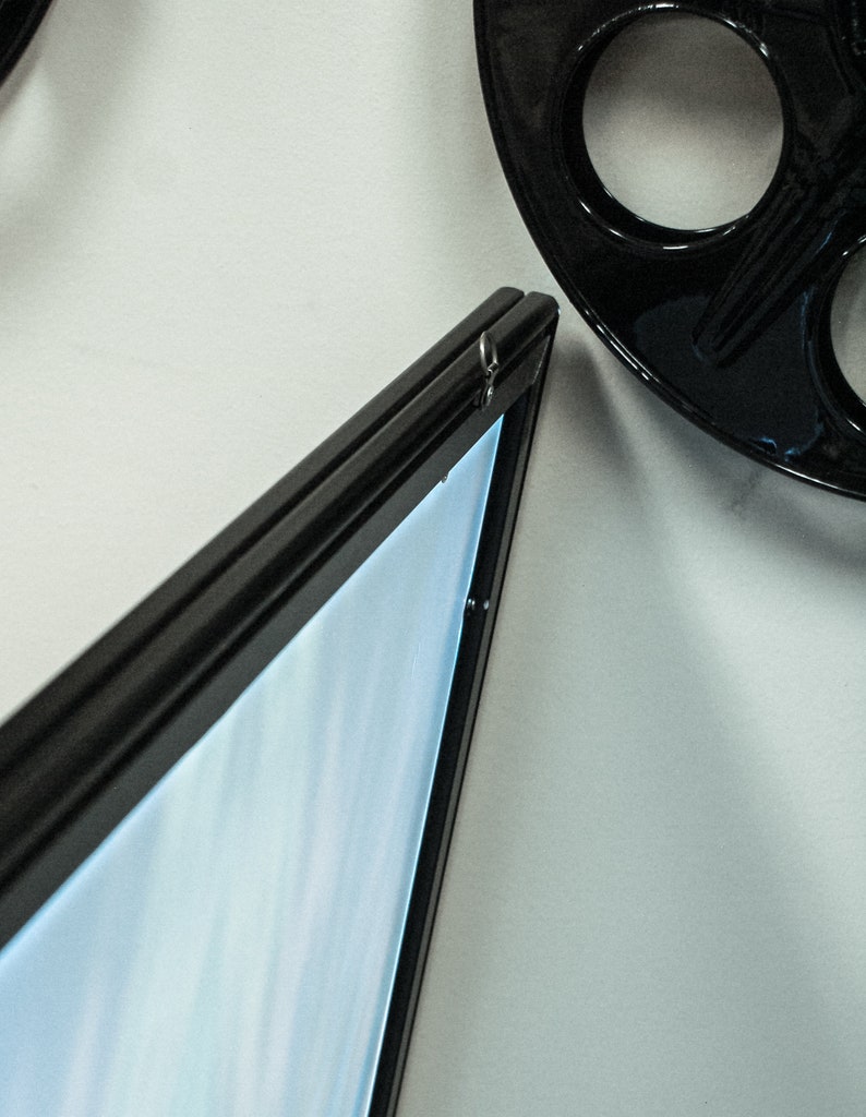 May include: A black picture frame with a light blue background. The frame is hanging on a white wall.