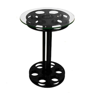 May include: Black metal side table with a round glass top. The base of the table is shaped like a film reel.