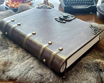 Pode incluir: Um diário encadernado em couro marrom com um fecho de metal e detalhes decorativos. O diário tem um aspecto envelhecido e está fechado.