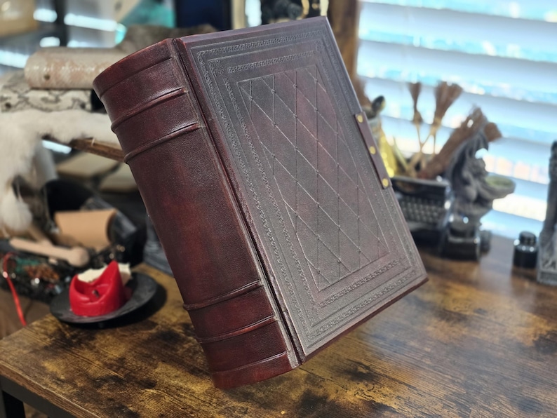 May include: A dark brown leather-bound journal with a decorative embossed pattern on the cover. The journal has a spine with raised bands and is closed.