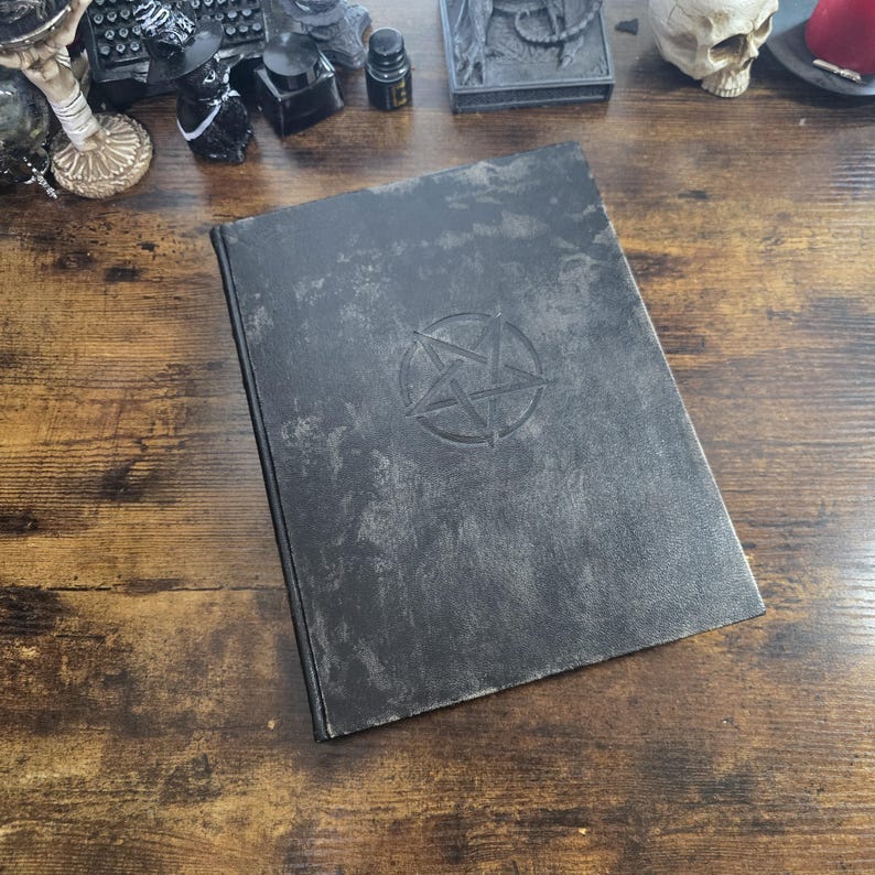 K&ouml;nnte beinhalten: Ein schwarzes, ledergebundenes Tagebuch mit einem gepr&auml;gten Pentagramm auf dem vorderen Umschlag. Das Tagebuch hat einen abgenutzten, antiken Look.