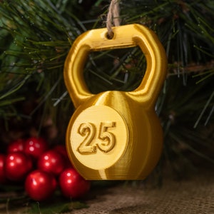 May include: Gold-colored Christmas ornament shaped like a kettlebell with the number 25 printed on it.
