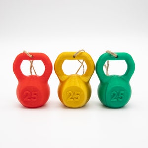May include: Three small, colorful, 3D printed kettlebells with the number 25 printed on each. The kettlebells are red, yellow, and green.