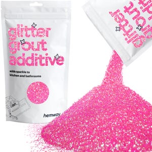 May include: Pink glitter grout additive in a white resealable bag with the text "glitter grout additive" and "adds sparkle to kitchen and bathrooms". The bag is pouring out the glitter onto a white surface.