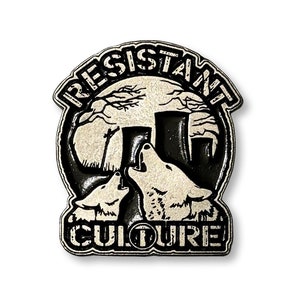 May include: Black and white enamel pin with a circular design. The pin features two wolves howling at the moon with a cityscape in the background. The text "RESISTANT CULTURE" is written around the outside of the circle.