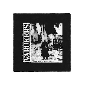 Puede incluir: Parche en blanco y negro con el texto "VARUKERS" y "HOW DO YOU SLEEP?????"  El parche presenta una imagen en blanco y negro de una persona con abrigo de pie en una ciudad destruida.