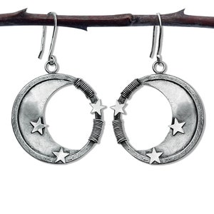 May include: Silver crescent moon earrings with four small stars on each earring. The earrings are hanging from a branch.