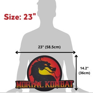 K&ouml;nnte beinhalten: Ein Mortal Kombat-Logo, 58,5 cm breit und 36 cm hoch, mit einer schwarzen Drachensilhouette auf rotem und gelbem Hintergrund. Die Worte "MORTAL KOMBAT" sind in goldfarbenen Buchstaben dargestellt.