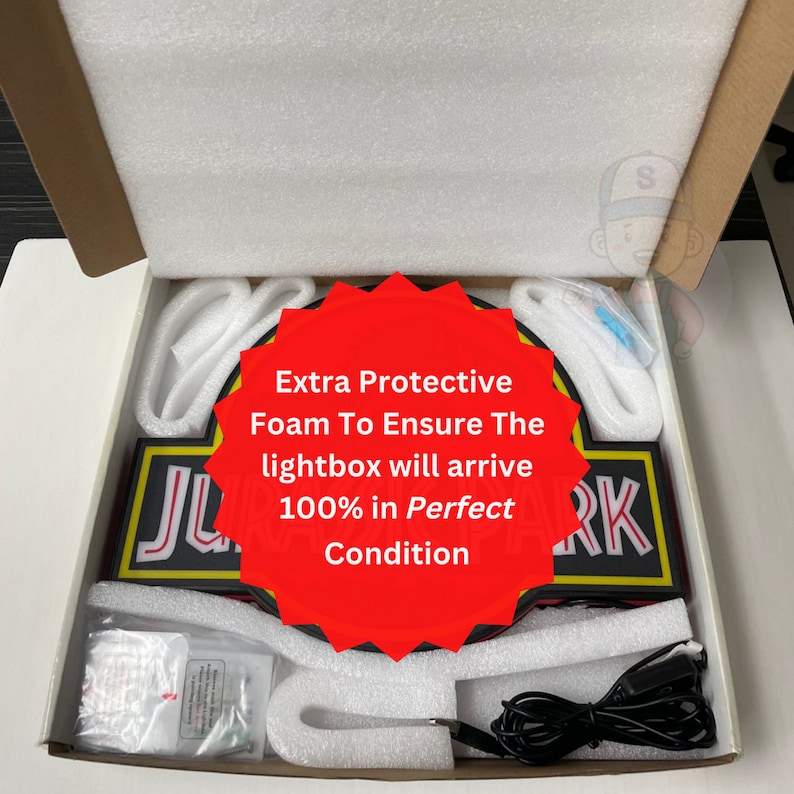 May include: A rectangular Jurassic Park lightbox packaged inside a cardboard box with white protective foam inserts. The lightbox features black, red, and yellow colors with white lettering. A black power cord and small hardware bag are included.