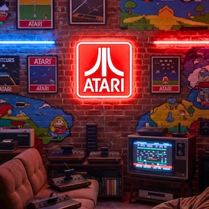 May include: A retro gaming room with a brick wall featuring Atari posters and a neon sign. A vintage television displays a game screen, with consoles and controllers on display. A brown sofa and pixelated world map complete the scene.