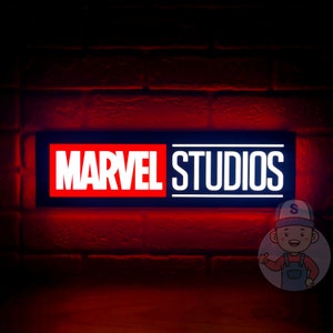 May include: A red and black sign with white text that reads "MARVEL STUDIOS" against a brick wall background.