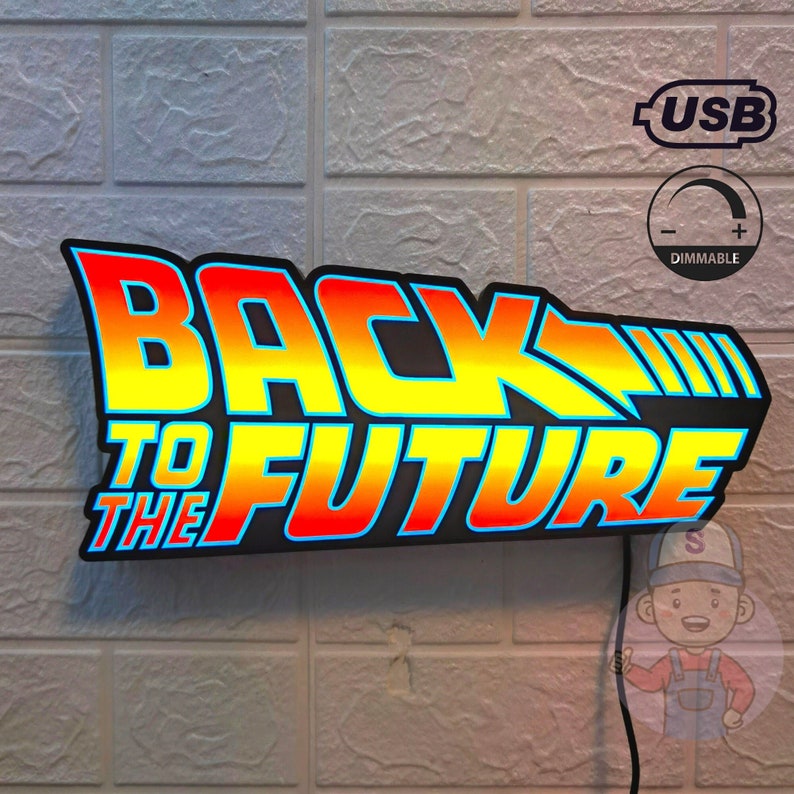 Op de afbeelding: Een verlicht bord met de tekst "BACK TO THE FUTURE" in een gele, oranje en rode kleurengradatie. Het bord heeft een zwarte rand en bevat een USB-poort en dimfunctie. Gemonteerd op een bakstenen muur, met een stroomkabel.