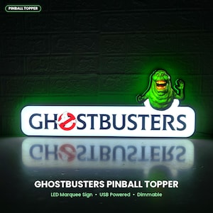 May include: A rectangular LED pinball topper sign featuring the Ghostbusters logo with black text on a white background and a green glowing Slimer character figure attached to the top right corner. The sign is USB powered and dimmable.