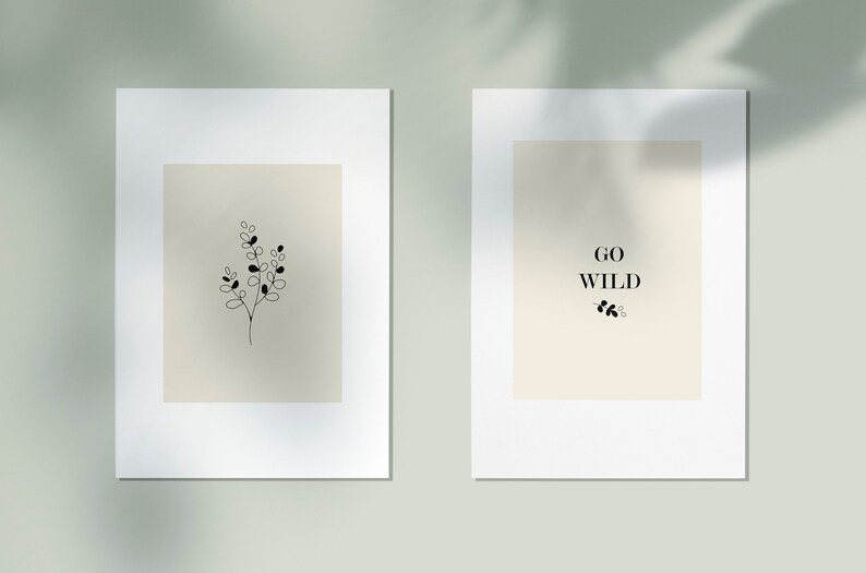 May include: Two minimalist prints with white frames. The print on the left features a simple line drawing of a sprig of leaves. The print on the right features the text "GO WILD" with a small sprig of leaves below.