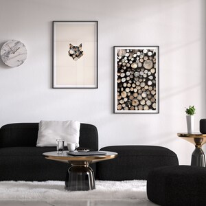 May include: A black sectional sofa with a white pillow sits in front of a white wall with two framed prints. One print features a geometric wolf design, and the other features a stack of wooden logs. A round marble clock hangs on the wall. A black and gold coffee table sits in front of the sofa. A small black ottoman sits in front of the coffee table. A small black side table with a gold top sits next to a window. A small potted plant sits on the side table.