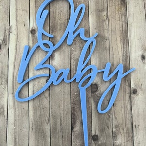 May include: A light blue cake topper with the words "Oh Baby" in a cursive font.