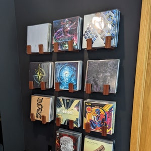 x9 sets of vinyl wall holders in mahogany wood mounted on a black wall, each holding around 15 vinyls.