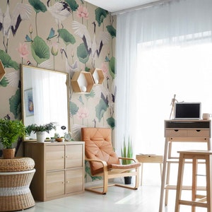 May include: A home office with a light brown standing desk, a laptop computer, and a brown leather chair. The wall is decorated with a wallpaper featuring white cranes, pink lotus flowers, and green leaves.