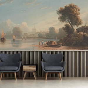 Puede incluir: Una pintura de acuarela que representa una escena de río con barcos, árboles y un pueblo en la distancia. La pintura está enmarcada y colgada en una pared sobre dos sillones grises y una mesa auxiliar de madera.