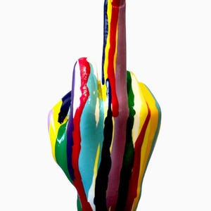 May include: A ceramic hand sculpture with the middle finger raised. The hand is painted with vertical stripes of various colors, including red, yellow, blue, green, and purple, with paint drips.