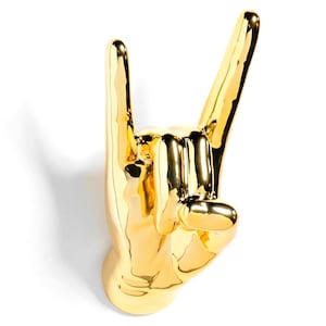 May include: A gold-colored hand sculpture in the 'rock on' gesture, with the index and pinky fingers extended. The sculpture has a glossy finish and is set against a white background.