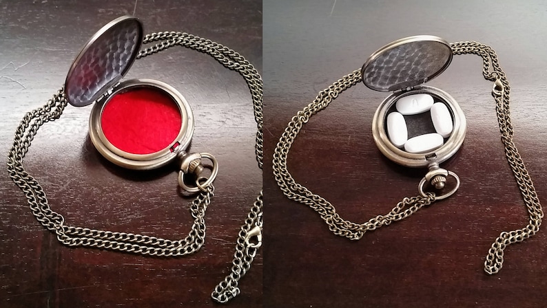 May include: A gold-toned necklace with a round locket pendant. The locket is open and has a red velvet interior. The locket is also shown open with four white pills inside.