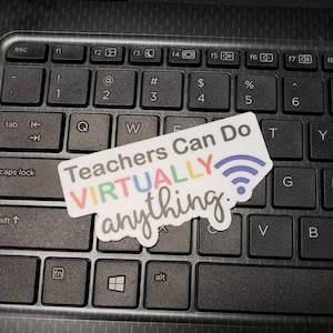 May include: A white sticker with colorful text that reads "Teachers Can Do VIRTUALLY anything." The sticker is placed on a black laptop keyboard.