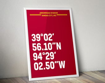 Puede incluir: Una impresión enmarcada en blanco con fondo rojo y texto blanco. El texto dice "ARROWHEAD STADIUM KANSAS CITY, MO 39°02′ 56.10″N 94°29′ 02.50″W".