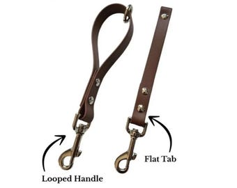 May include: Two brown leather-like straps with silver-toned metal swivel snap hooks. One strap features a looped handle, while the other is a straight flat tab. Both straps are secured with silver metal rivets. Text labels read Looped Handle and Flat Tab.