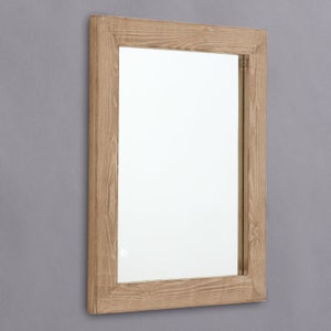 May include: A rectangular wooden framed mirror with a light brown wood finish. The mirror has a simple design and a clean, modern look.