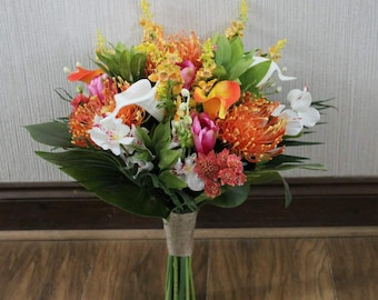 May include: A tropical bridal bouquet with orange, pink, and white flowers, including protea, calla lilies, and orchids. The bouquet is wrapped in twine and has lush green foliage.