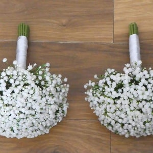 May include: Two white baby's breath bouquets tied with white satin ribbon.