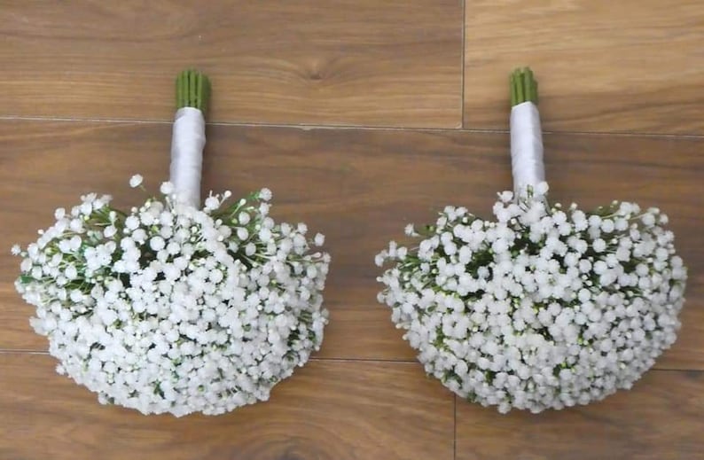 May include: Two white baby's breath bouquets tied with white satin ribbon.