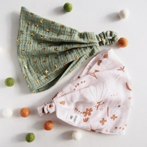 Op de afbeelding: Twee stoffen hoofdbanden, een groene met gouden sterren en een roze met bruine abstracte ontwerpen. Beide hoofdbanden hebben een geplooide elastische band.