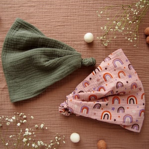 Op de afbeelding: Twee baby spuugdoeken, een groene en een roze met een regenboog- en sterrenpatroon.