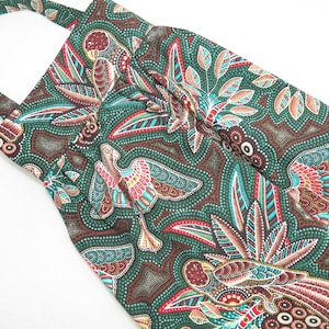 May include: A green tote bag with a colorful bird and leaf pattern. The fabric features a repeating design of birds, leaves, and dots in shades of red, brown, and teal. The bag has a handle.