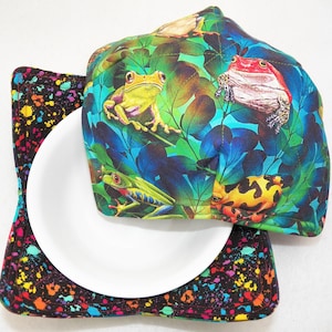 May include: A bowl cozy with a black and white splatter pattern and a removable lid featuring a colorful frog and leaf design.