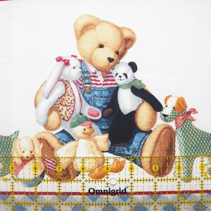 Pode incluir: Tecido branco com um padr&atilde;o repetido de ursos de pel&uacute;cia, um panda, um coelho e c&atilde;es. O urso de pel&uacute;cia usa macac&atilde;o e uma camisa listrada. A borda apresenta um padr&atilde;o de losangos azuis e brancos e uma faixa vermelha.