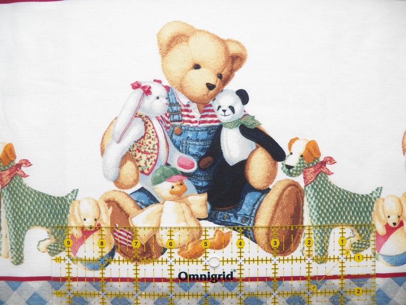 Pode incluir: Tecido branco com um padr&atilde;o repetido de ursos de pel&uacute;cia, um panda, um coelho e c&atilde;es. O urso de pel&uacute;cia usa macac&atilde;o e uma camisa listrada. A borda apresenta um padr&atilde;o de losangos azuis e brancos e uma faixa vermelha.