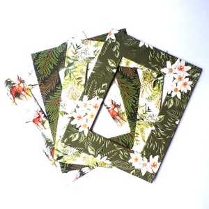 May include: Set of four green picture frames with a white floral and deer design. The frames are made of cardboard and have a rustic look.