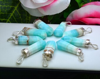 May include: A collection of blue and white gemstone pendants with silver-colored metal caps and loops. The pendants are arranged in a circular pattern on a white surface, with a floral background.
