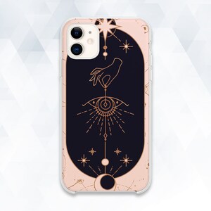 May include: A phone case with a pink and black design featuring a hand holding a celestial eye with a star and moon motif.