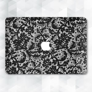 May include: A black and white lace pattern covers the top of a laptop. The design features a detailed floral lace motif. The Apple logo is visible in the center of the laptop.